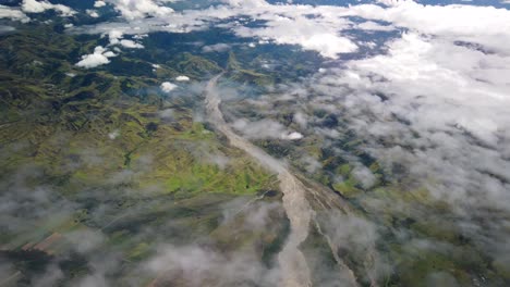 flying over rugged papua new guinea mountains and river above clouds