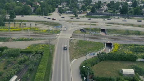 Drohnenaufnahmen-Von-Autos,-Die-Im-Sommer-Hinter-Einem-Bahnübergang-Auf-Einen-Zug-Warten,-Der-Vorbeifährt-Und-In-Tallinn,-Estland,-Das-Baltikum-überquert