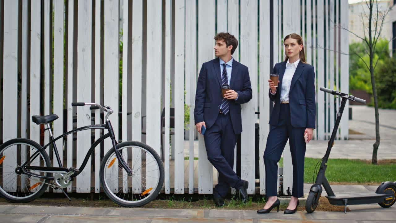 Office colleagues enjoy coffee standing by scooter and bicycle outdoors
