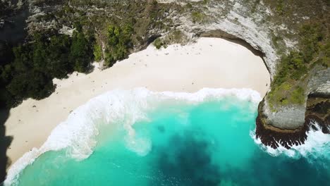 bird's eye drone shot above waves crashing onto kelingking beach on the island of nusa penida, indonesia