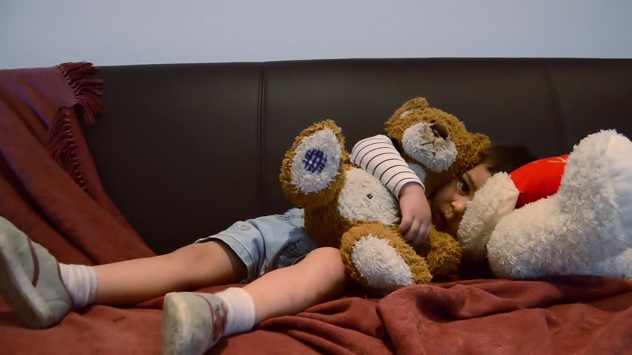 Cute tired toddler falling asleep on the couch - funny baby face expressions