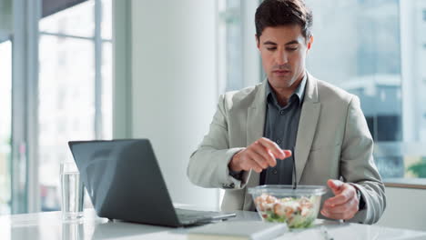 man eating lunch while working on laptop in the office