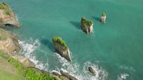 Tres-Columnas-De-Roca-Hermanas-Erguidas-En-La-Costa-De-Nueva-Zelanda,-Disparo-De-Drone