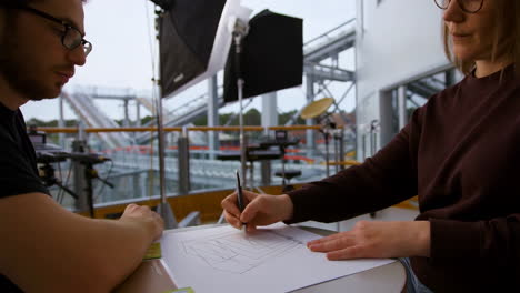 two designers or artists collaborating on a drawing in a modern studio environment with photography equipment