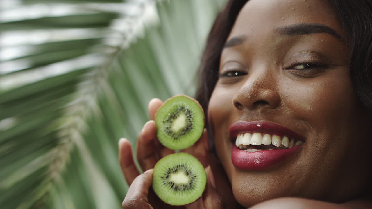 Kiwi nas mãos de uma linda garota segurando um círculo de rostos em um close-up de retrato de africana