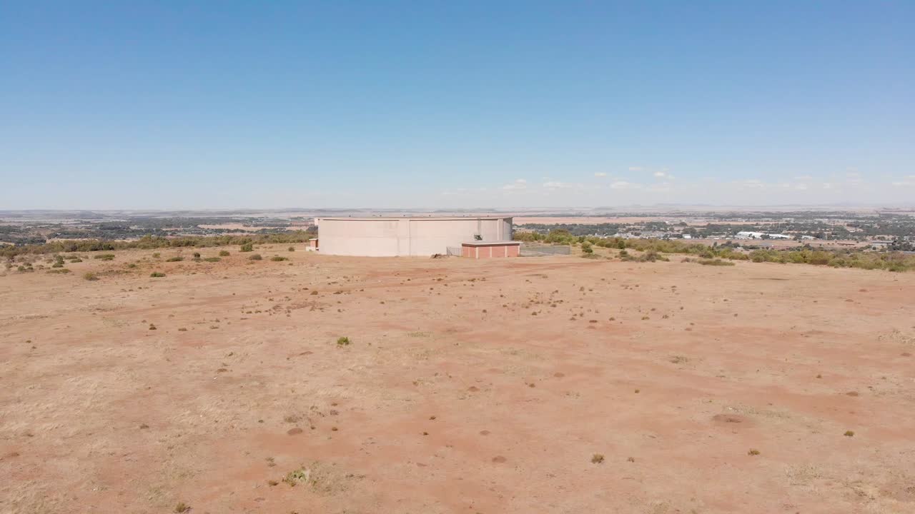 drone revela toma de tanque de suministro de agua que suministra agua a una ciudad en el fondo en un día soleado