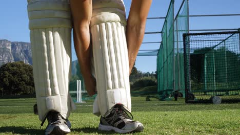 un joueur de cricket attache ses pads de battage lors d'une séance de pratique