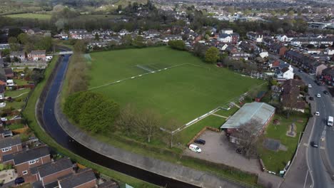 aerial drone shot over rural suburb football pitch in housing estate, england