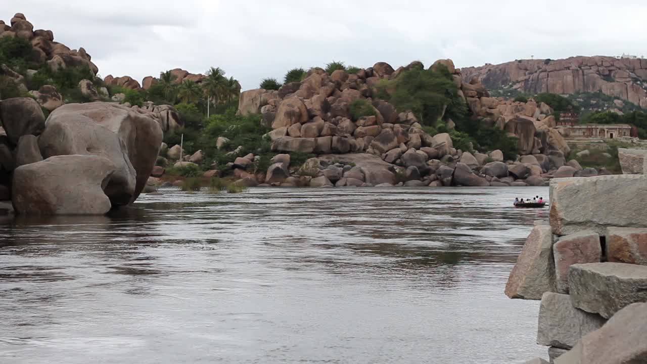 Wide shot of a coracle Boat Floating Among Ancient Boulders in Hampi, India