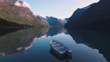 Hermoso-Paisaje-De-Un-Pequeño-Bote-De-Remos-De-Madera-Tendido-En-Un-Gran-Lago-En-Un-Día-Soleado,-Rodeado-De-Grandes-Montañas-En-Noruega-Lovatnet