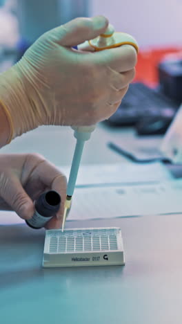 Laboratory technician is filling rack with special liquid from the small plastic jar on the table. Medical tests. Clinical diagnostic laboratory equipment. Vertical video