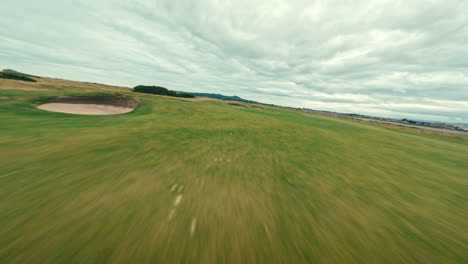 fpv drone flyover green fairways on ireland links golf course pov