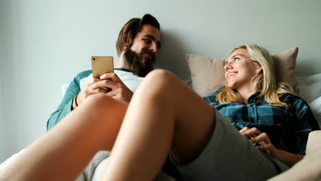 couple using mobile phone on bed at home 4k