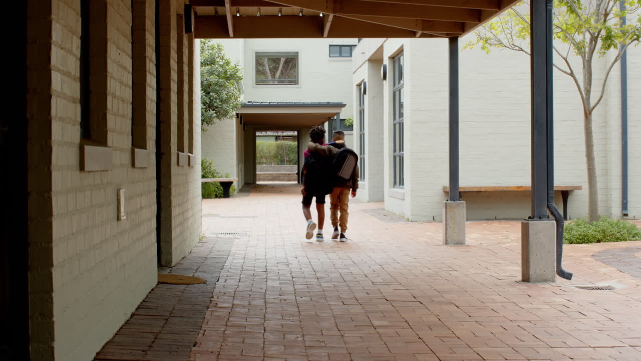 Multiracial boys walking together in school hallway, sharing moment of friendship