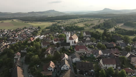 drone footage flying over the historic old town of aach, baden-württemberg, providing a detailed view of the rooftops, church tower, and the surrounding countryside.