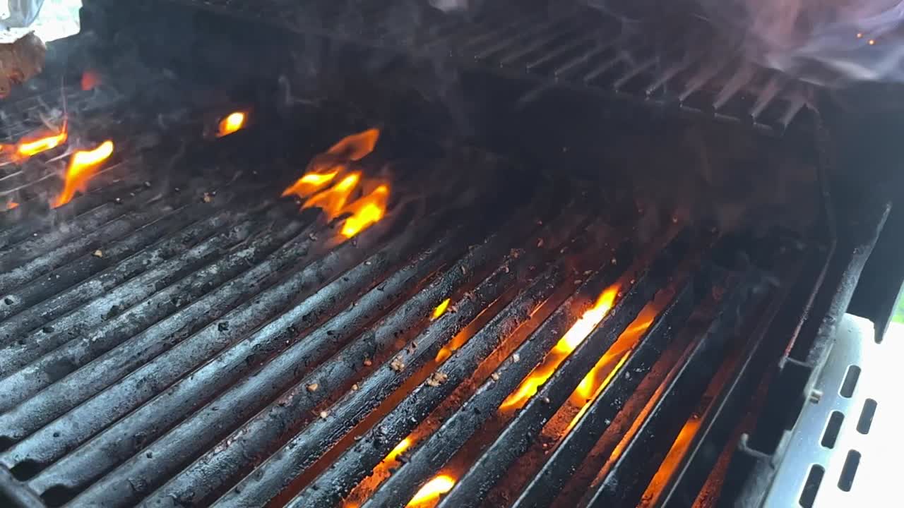Pinze usate per rimuovere una bistecca cotta da una griglia fiammeggiante
