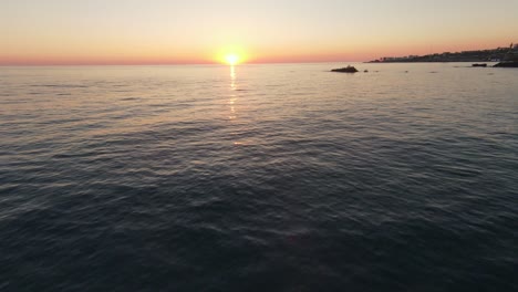 Vuelo-Fpv-Sobre-El-Agua-A-Lo-Largo-De-La-Costa-De-La-Ciudad-De-Batroun-Durante-La-Puesta-De-Sol-Dorada-En-El-Horizonte,-Líbano