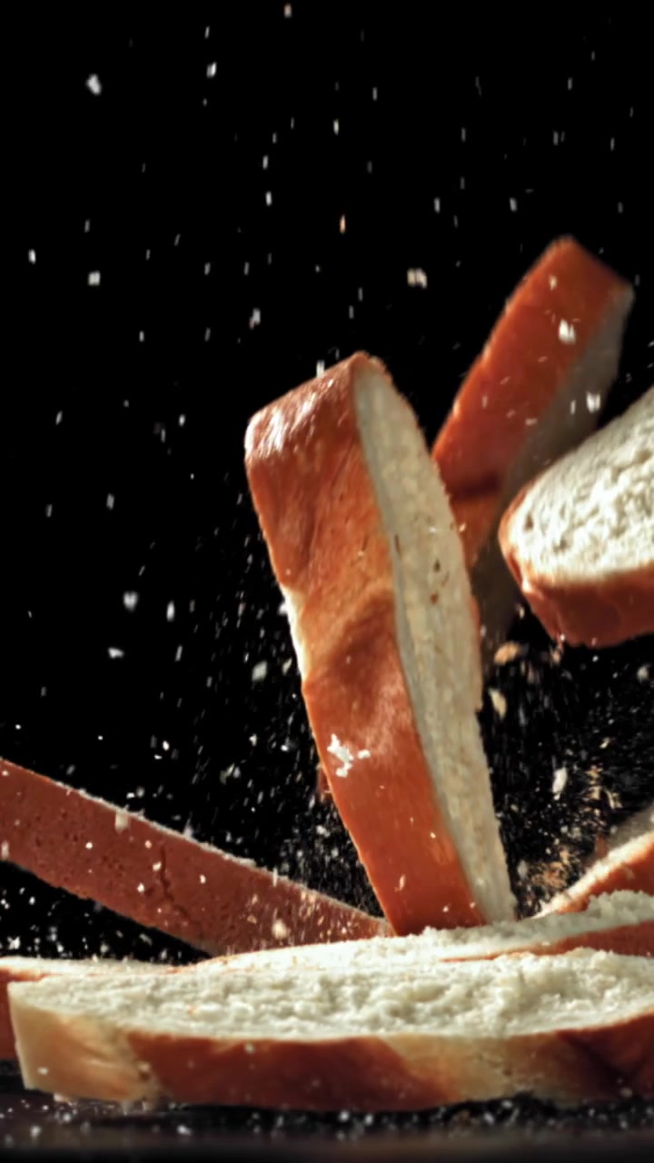 Slow Motion of Sliced Bread Falling with Crumbs on Black Background