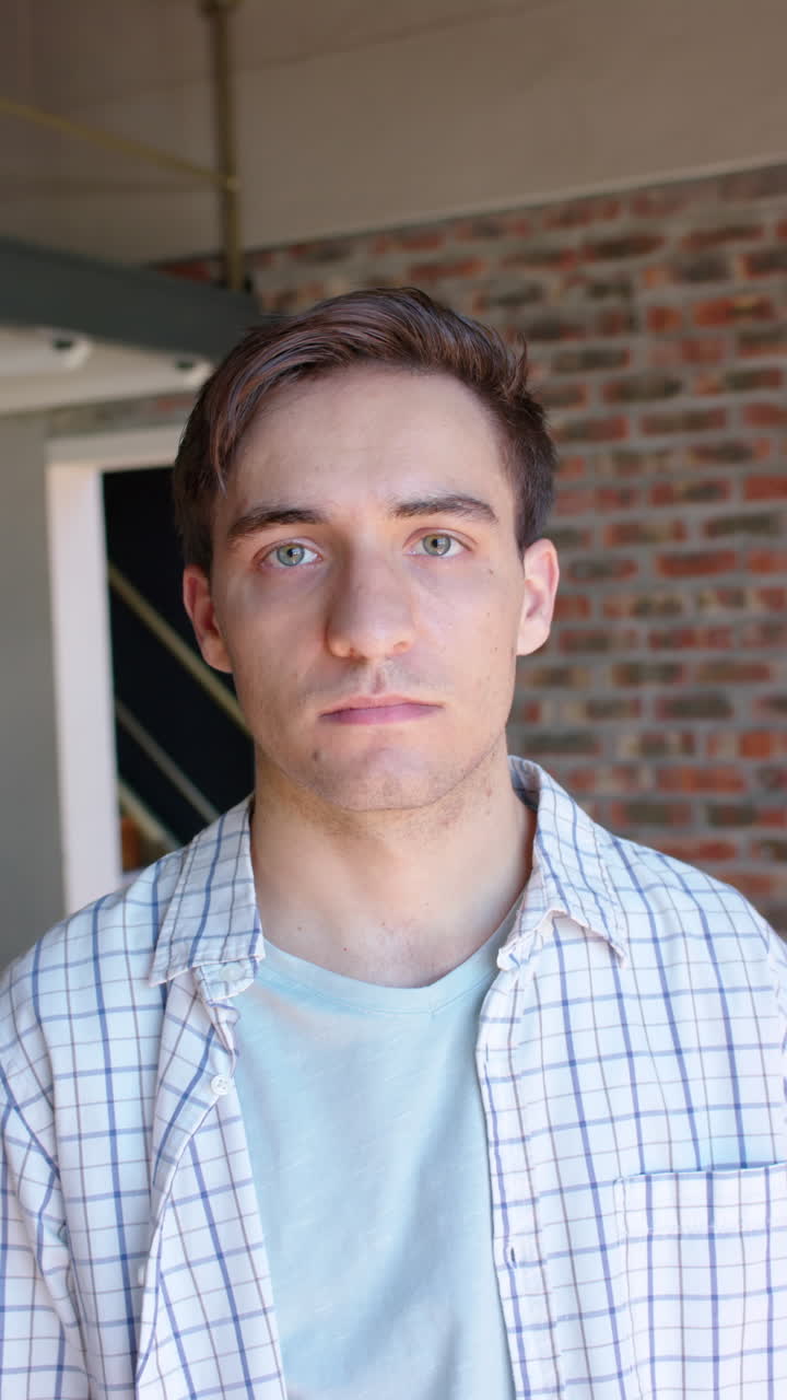 Vertical video portrait of serious caucasian businessman looking to camera in office, slow motion