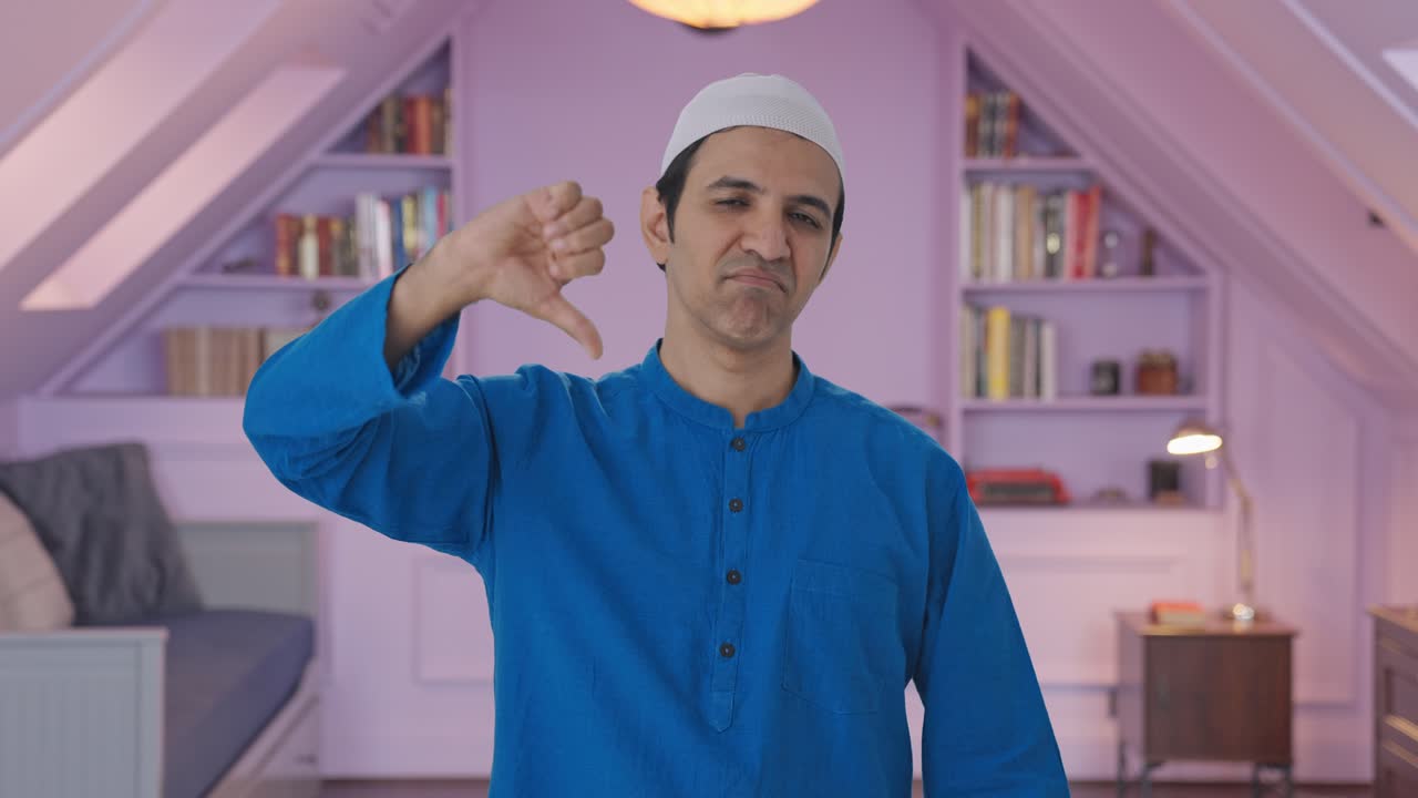 hombre musulmán decepcionado mostrando los pulgares hacia abajo