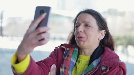 mujer caucásica de mediana edad sonriente hablando en un teléfono inteligente