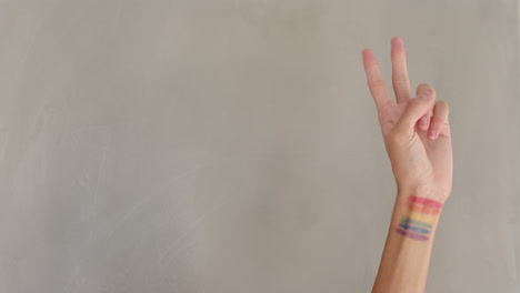 hand with rainbow flag tattoo making peace sign, symbolizing lgbtq+ pride