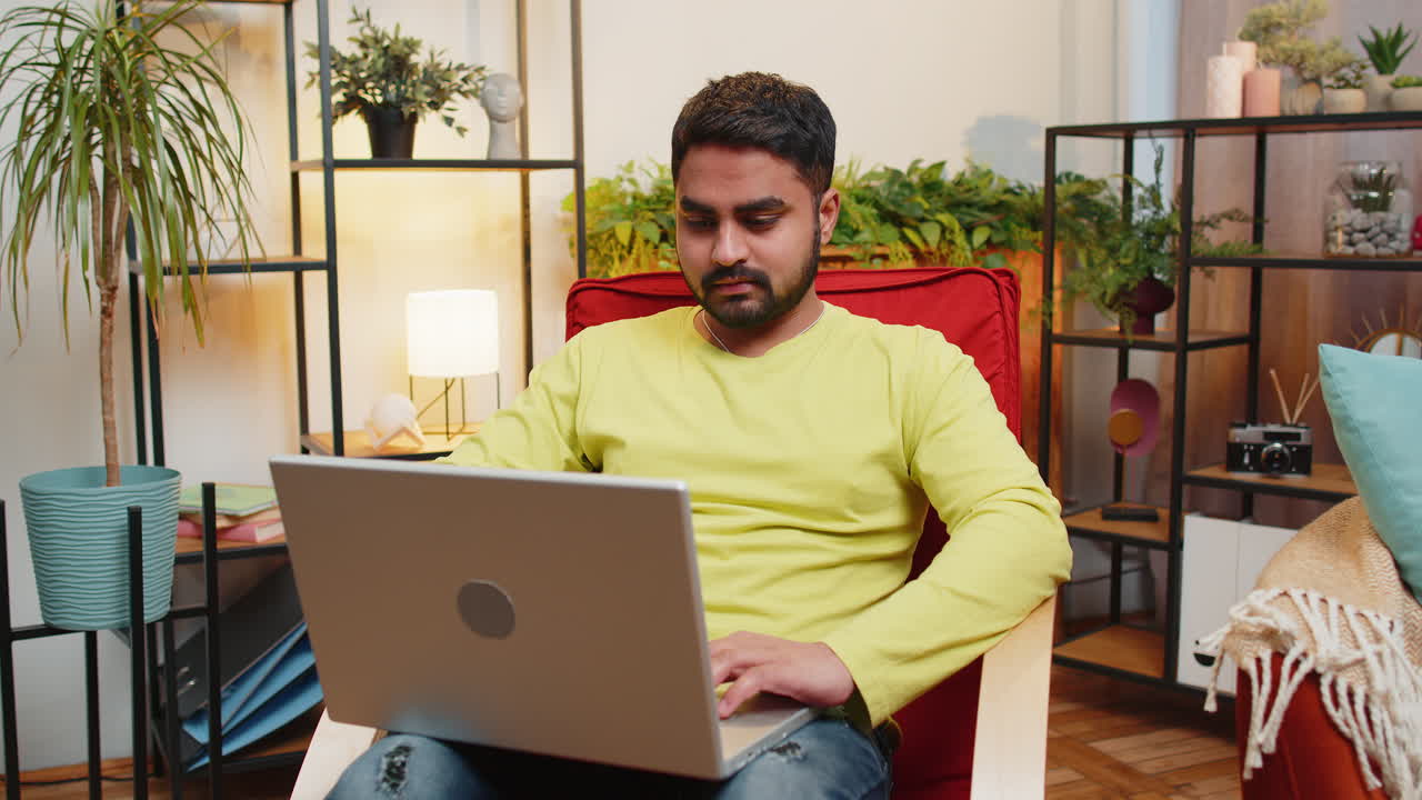 Young man freelancer sitting on chair close laptop pc after finishing work in living room at home