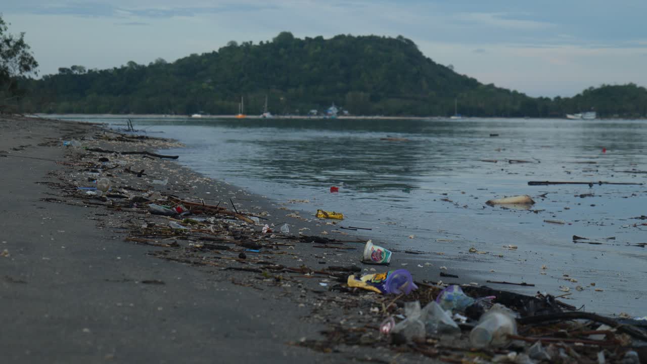 Slow-motion mid shot of rubbish in shore line on a beach in Lombok, Indonesia