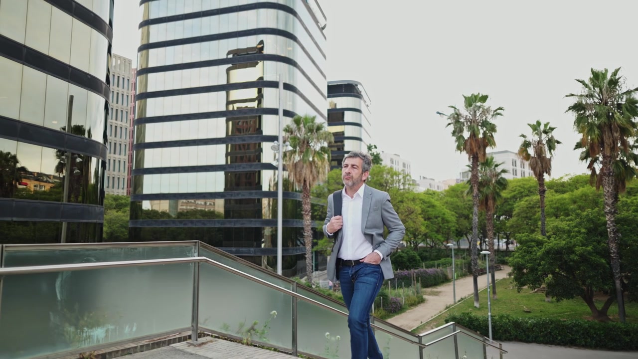 Uomo maturo che cammina attraverso un paesaggio urbano moderno con edifici in vetro