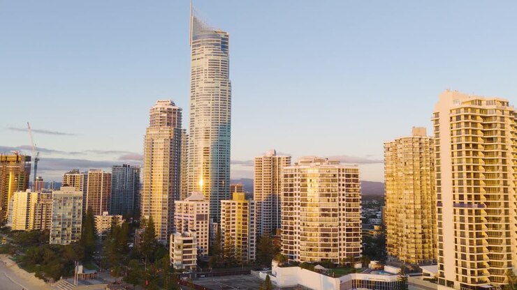 Drone footage captures Gold Coast's skyline with skyscrapers and ocean during golden hour, highlighting urban architecture and coastal beauty
