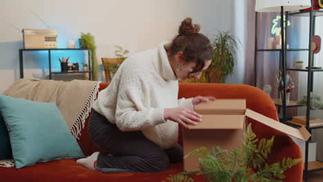 happy young woman shopper unpacking cardboard box delivery parcel online shopping purchase at home