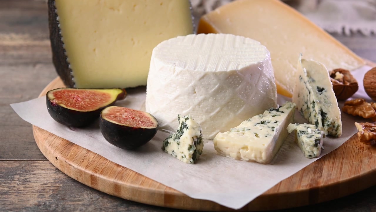 Board of different cheeses with nuts, figs and grapes