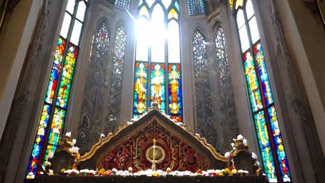 sunlight streaming through colorful stained glass windows illuminates the altar in a serene church interior