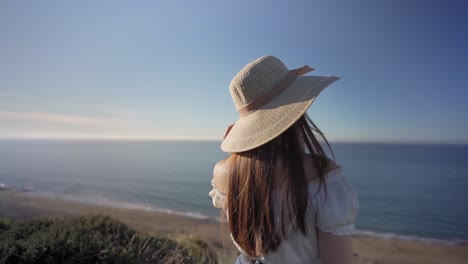 frau steht auf einer grünen, grasigen landschaft neben dem meer