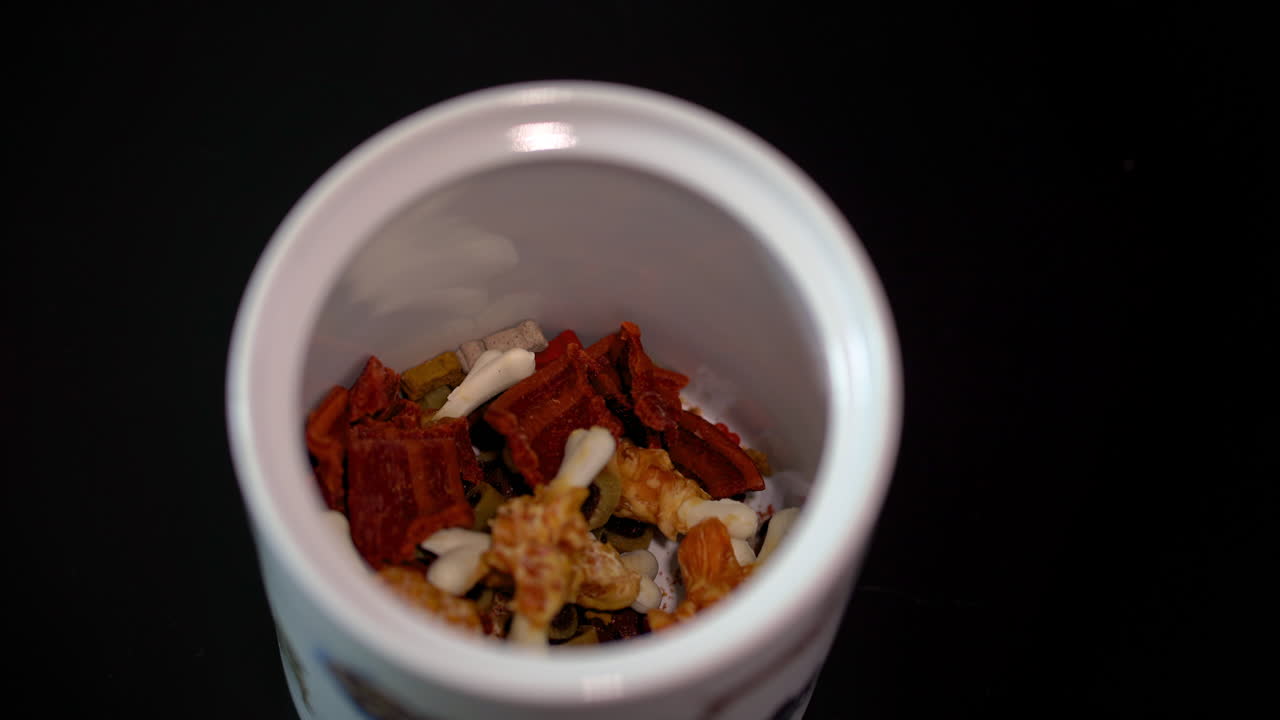 Hand Reaching into a Jar of Dog Treats and Nuts