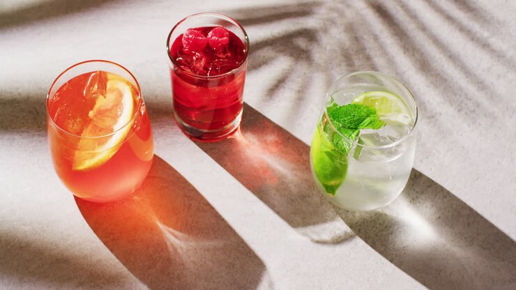 Close up of drinks with orange, raspberry and lemon over shadow