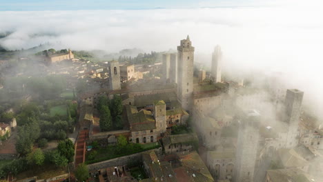 foggy landscape in san gimignano town in italy - aerial drone shot