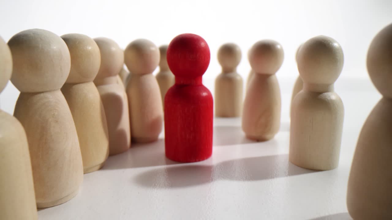 Red Wooden Figure Standing Out in a Crowd of Identical Figures