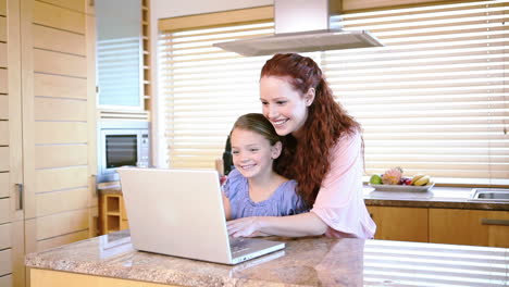 Smiling-mother-using-a-laptop-with-her-daughter