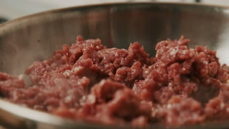 close up on meat paste being fried in metal frying pan