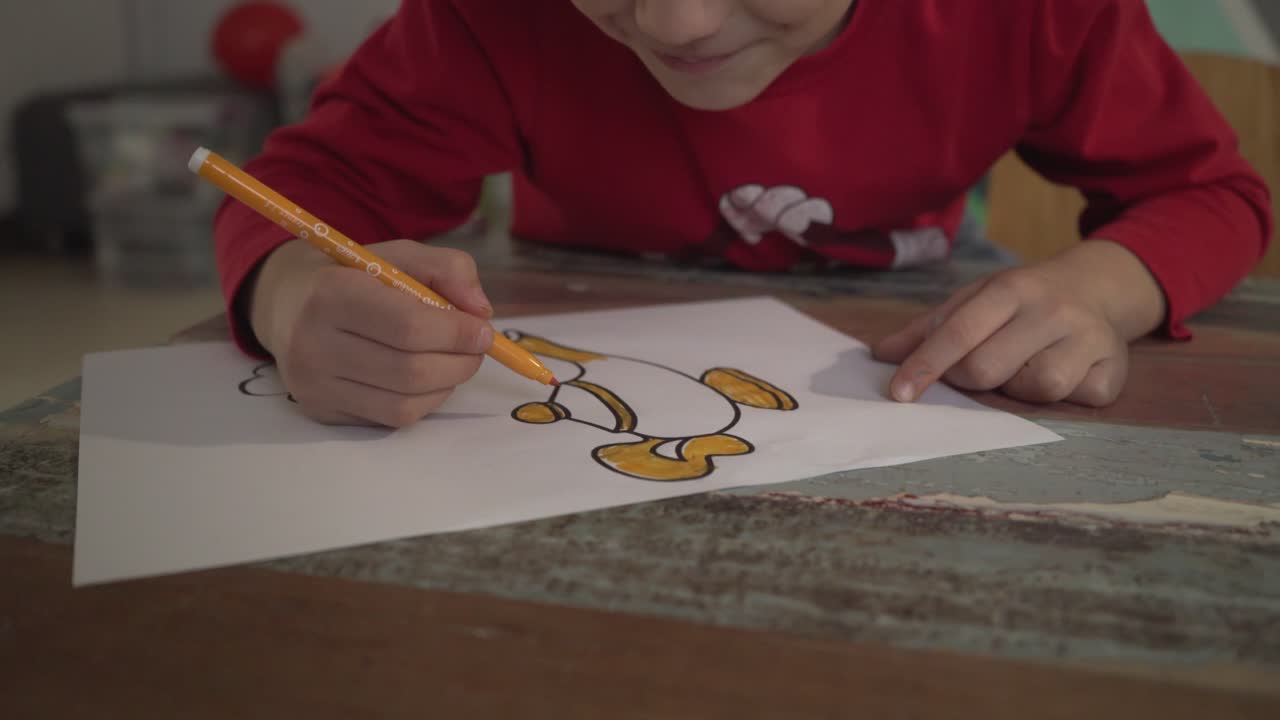 실내에서 노란색 마커를 사용하여 마술 램프 그리기를 그리는 백인 소년