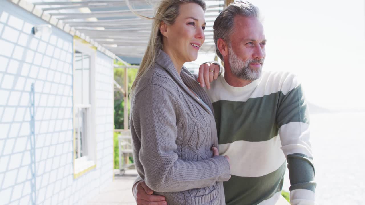 feliz pareja caucásica madura de pie en la terraza junto al mar