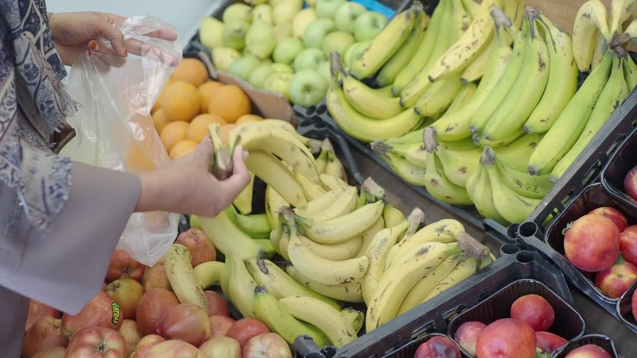 mujer comprando plátanos y otras frutas en una tienda de comestibles