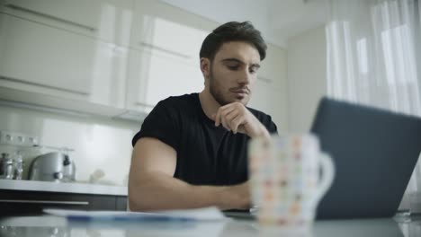 hombre serio trabajando en una computadora portátil en casa. hombre de negocios reflexivo