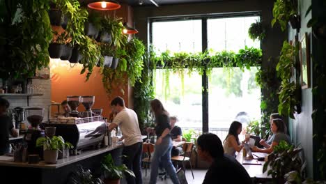 a lively coffee shop scene: people enjoying their time surrounded by lush greenery and aroma of fresh brews in a cozy, inviting atmosphere