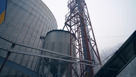 tanks, ladders and other premises at the grain storage factory. coming closet to a big cistern with metal ladder to it. close up.
