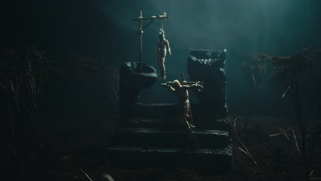 a miniature scene of the mummified dolls hanging on the gallows at night