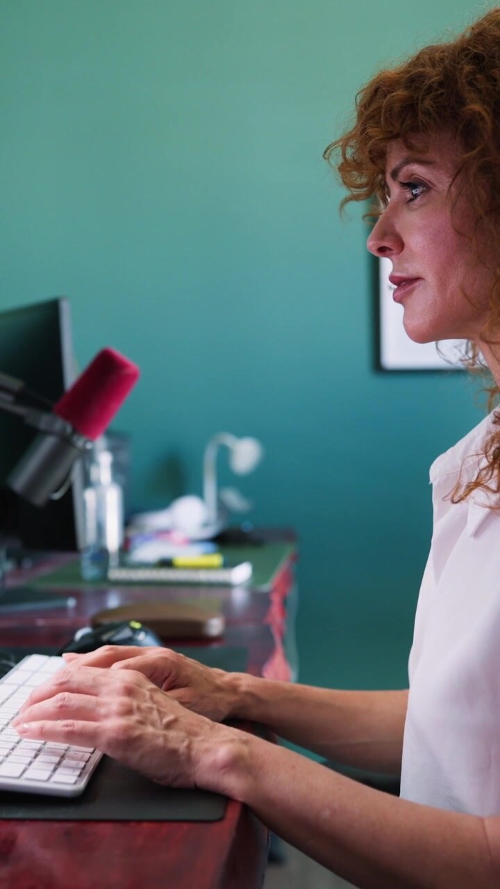 Donna con capelli rossi ricci che digita sulla tastiera del computer