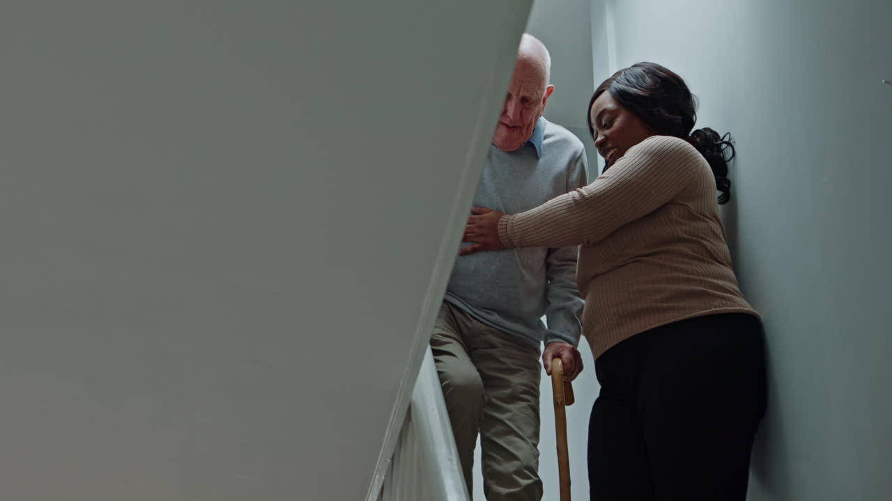 Elderly man being assisted by caregiver on stairs