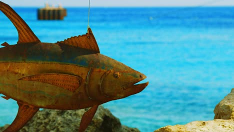 view of turquoise blue ocean to the rusty metal fish art in - focus rack shot